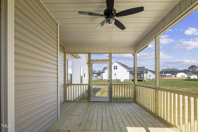 unfurnished sunroom featuring a residential view and ceiling fan