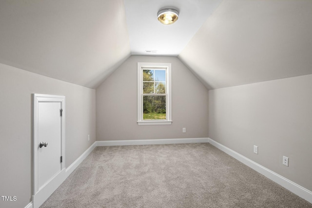 additional living space with baseboards, vaulted ceiling, visible vents, and carpet floors