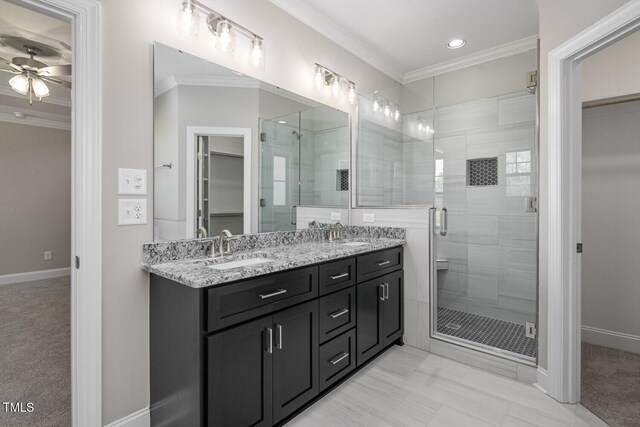 full bathroom featuring a ceiling fan, a sink, crown molding, and a shower stall