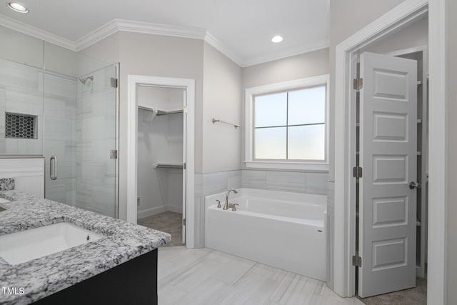 bathroom featuring a stall shower, crown molding, vanity, a garden tub, and a spacious closet