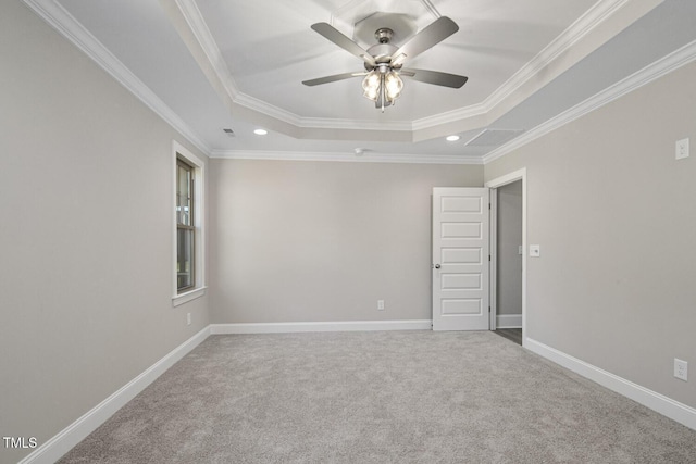 spare room featuring a tray ceiling, carpet, baseboards, ceiling fan, and ornamental molding