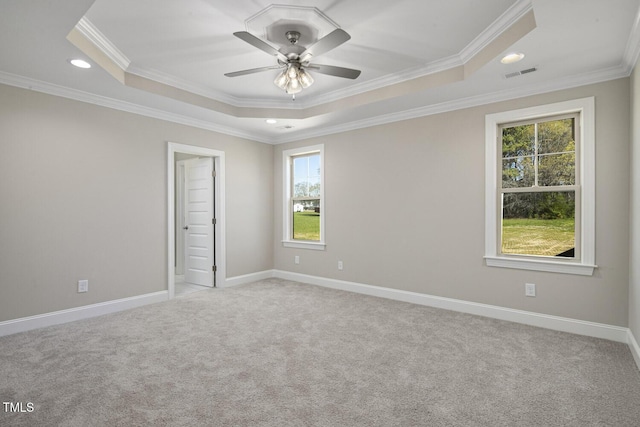 empty room with visible vents, crown molding, baseboards, light carpet, and a tray ceiling