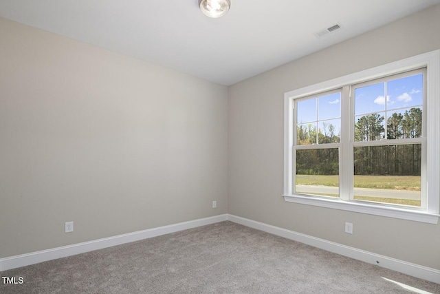 spare room featuring baseboards, visible vents, and light colored carpet