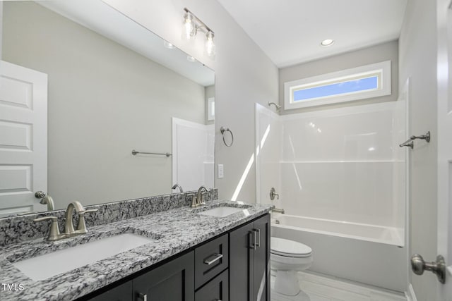 bathroom featuring toilet, a sink, double vanity, and bathtub / shower combination