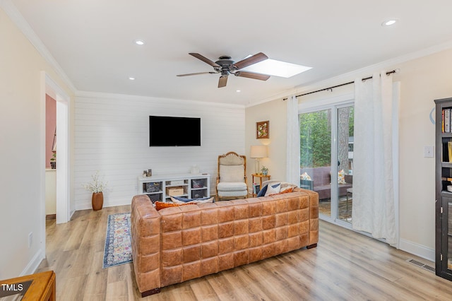 living area with light wood finished floors, ceiling fan, crown molding, visible vents, and baseboards