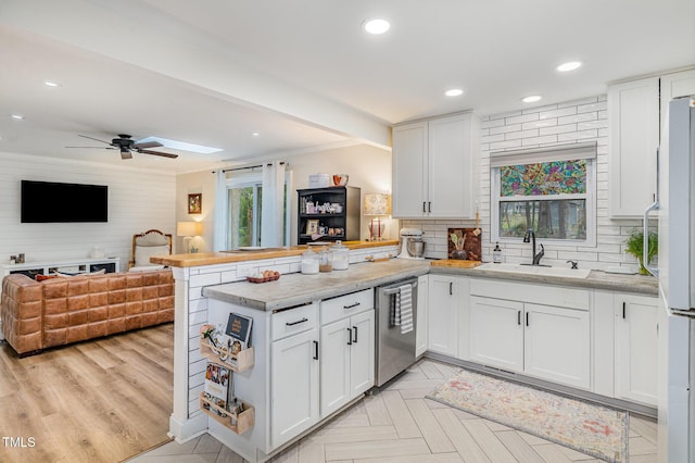 kitchen featuring a sink, a peninsula, light countertops, dishwasher, and open floor plan