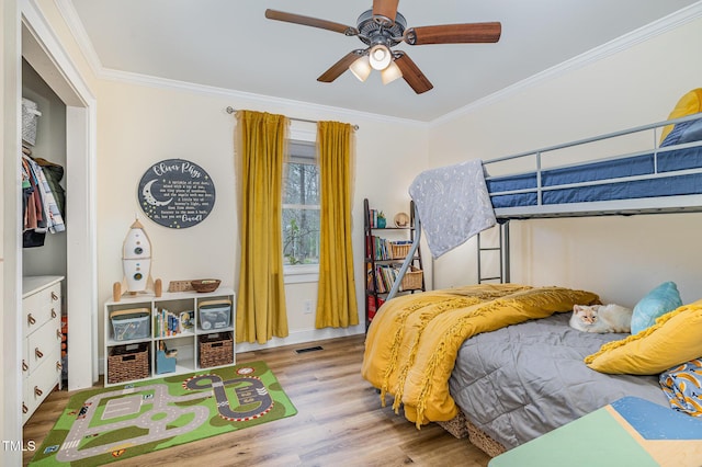 bedroom featuring crown molding, a ceiling fan, visible vents, and wood finished floors