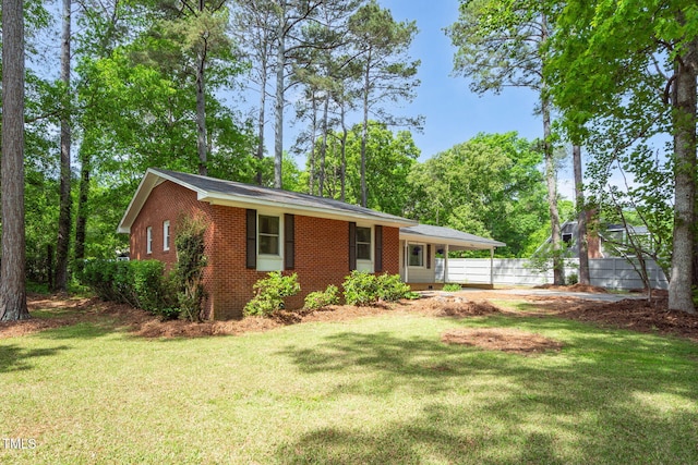 single story home featuring brick siding, fence, and a front yard