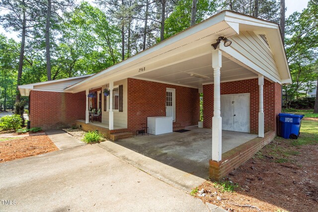 view of front of house featuring driveway, a carport, covered porch, and brick siding