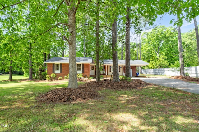 single story home with brick siding, fence, a carport, a front yard, and concrete driveway