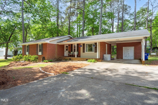 ranch-style home featuring crawl space, covered porch, aphalt driveway, a carport, and brick siding