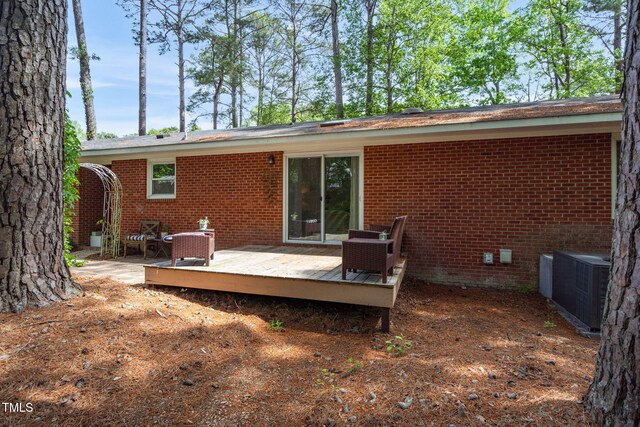 rear view of property featuring cooling unit, a wooden deck, and brick siding