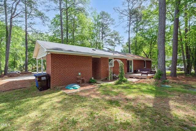 back of property featuring a deck, a yard, and brick siding
