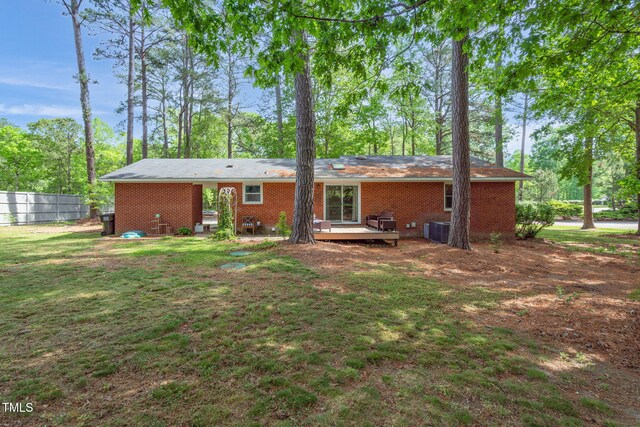 rear view of house with central air condition unit, a yard, brick siding, a deck, and fence