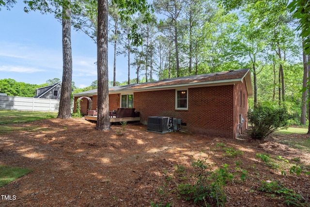 rear view of house featuring a wooden deck, central air condition unit, fence, and brick siding
