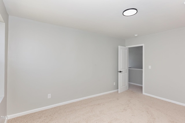 spare room featuring baseboards and light colored carpet