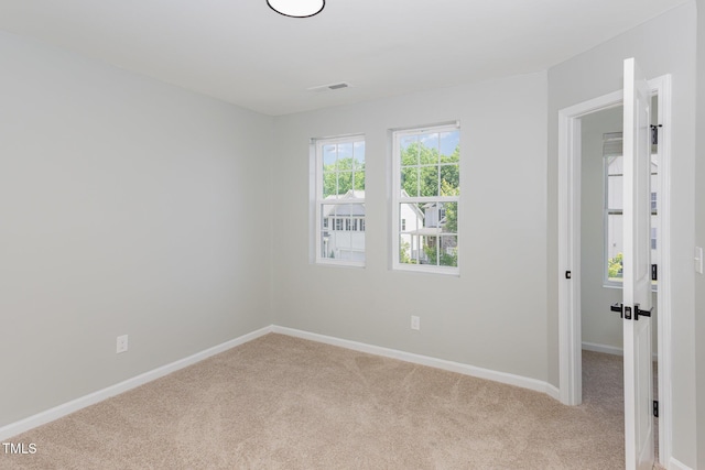 carpeted spare room featuring baseboards and visible vents
