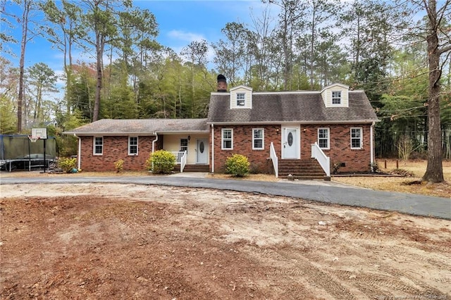 12621 Coble Dr, Laurinburg, NC 28352 - view of front of home with aphalt driveway, a trampoline, a shingled roof, brick siding, and a chimney