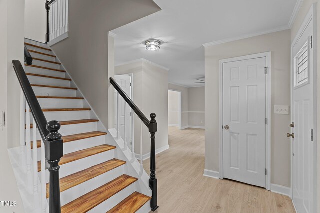 staircase with ornamental molding, baseboards, and wood finished floors