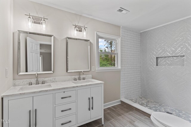 full bathroom featuring toilet, a sink, double vanity, and visible vents