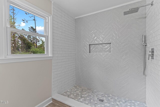 full bathroom with baseboards, ornamental molding, and tiled shower