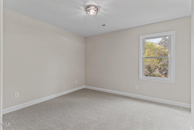 carpeted spare room featuring baseboards and visible vents