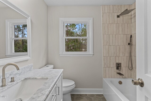 bathroom with vanity, toilet, baseboards, tile patterned floors, and  shower combination
