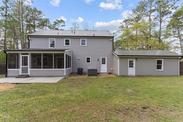 back of property with a sunroom, central air condition unit, a patio, metal roof, and a yard