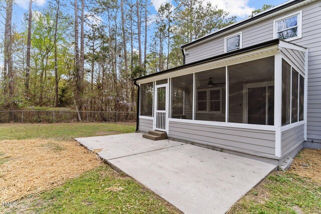 exterior space featuring a sunroom, a lawn, fence, and a patio area