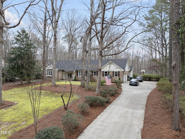 view of front of home featuring driveway, brick siding, a shingled roof, and a front yard