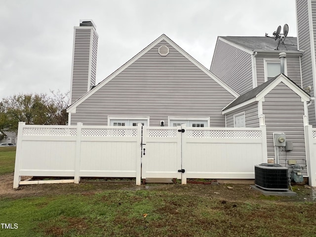 back of property featuring central air condition unit, a chimney, and fence