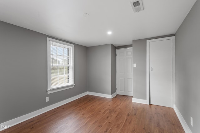 unfurnished bedroom with wood finished floors, baseboards, and visible vents