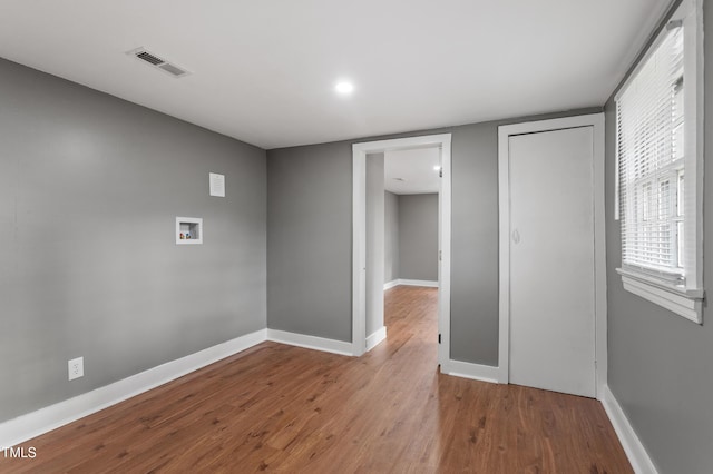 empty room featuring wood finished floors, baseboards, and visible vents