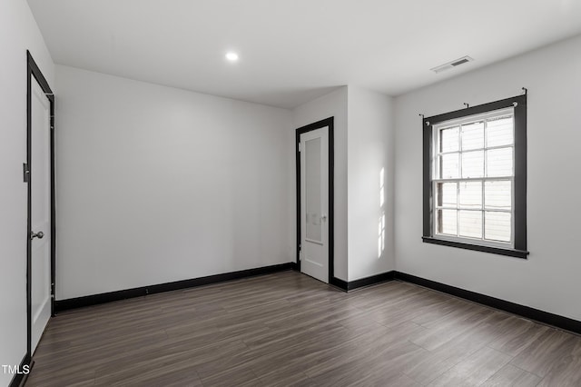 spare room featuring recessed lighting, dark wood-style floors, baseboards, and visible vents