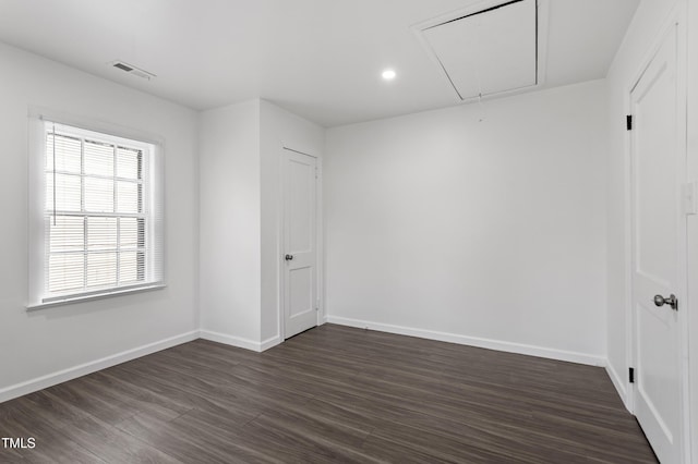 unfurnished room featuring attic access, baseboards, visible vents, and dark wood-style floors