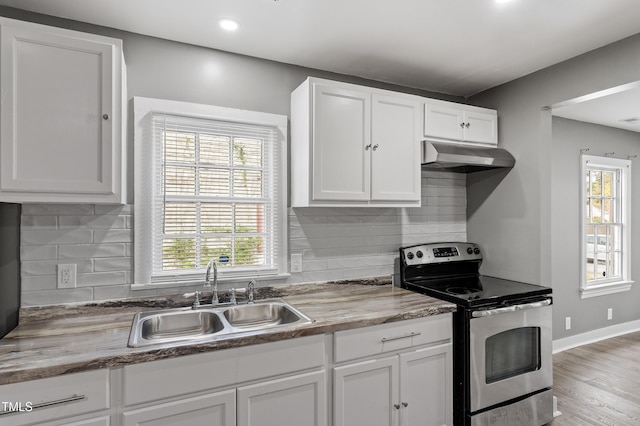 kitchen with a sink, under cabinet range hood, stainless steel electric range, and a healthy amount of sunlight