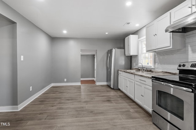 kitchen featuring decorative backsplash, light wood finished floors, stainless steel appliances, a sink, and extractor fan
