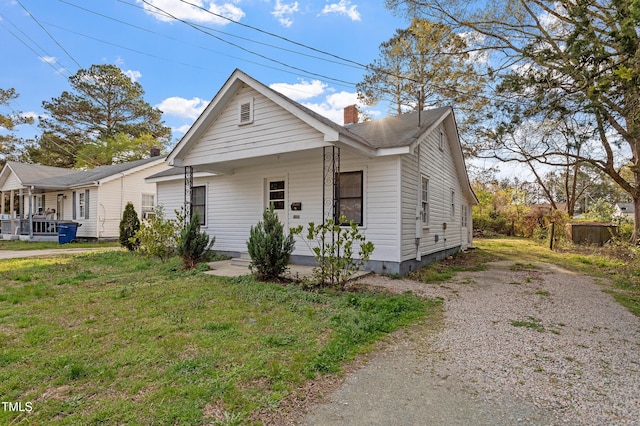 view of front facade featuring a front lawn, a chimney, and gravel driveway