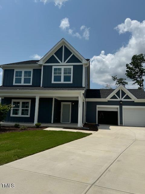 craftsman house featuring covered porch, driveway, a front lawn, and a garage