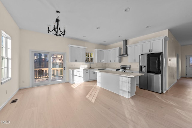 612 Lakeview Dr, Raleigh, NC 27603 - kitchen with appliances with stainless steel finishes, wall chimney exhaust hood, light wood-type flooring, a chandelier, and a sink