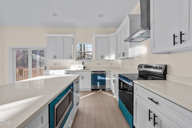 612 Lakeview Dr, Raleigh, NC 27603 - kitchen featuring wall chimney exhaust hood, appliances with stainless steel finishes, a sink, light wood finished floors, and white cabinetry