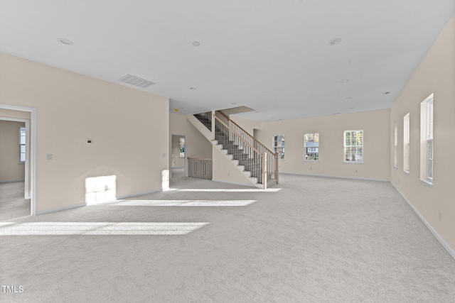 612 Lakeview Dr, Raleigh, NC 27603 - unfurnished living room with stairs, light colored carpet, and baseboards