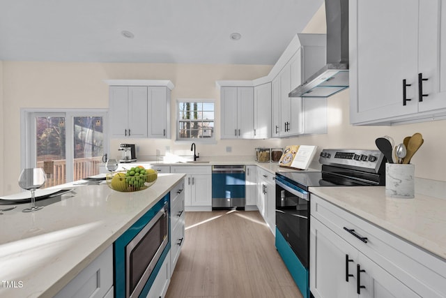 612 Lakeview Dr, Raleigh, NC 27603 - kitchen featuring wall chimney exhaust hood, stainless steel appliances, a sink, light wood finished floors, and white cabinets