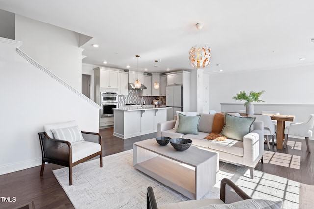 living area with baseboards, wood finished floors, recessed lighting, and an inviting chandelier