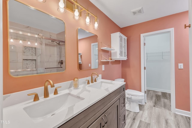 11035 Southwalk Ln, Raleigh, NC 27614 - bathroom featuring a stall shower, wood finished floors, toilet, double vanity, and a walk in closet