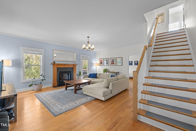 living area with stairs, baseboards, a chandelier, a fireplace with flush hearth, and light wood finished floors