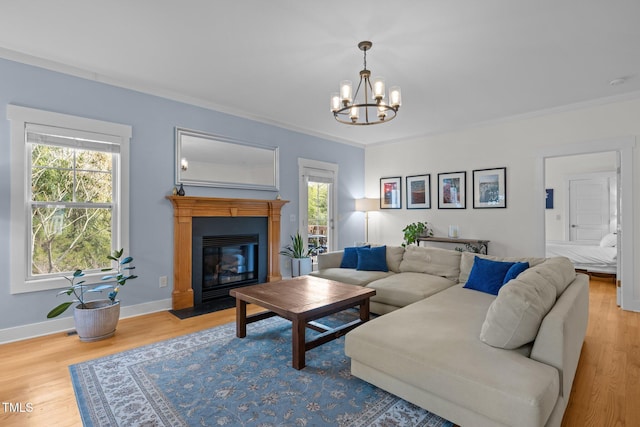 living room featuring an inviting chandelier, baseboards, a fireplace with flush hearth, wood finished floors, and ornamental molding