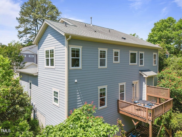 rear view of house featuring a shingled roof and a deck