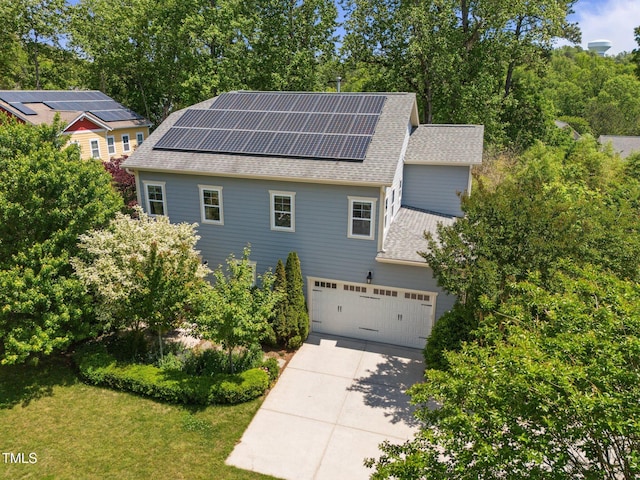 view of front of house featuring solar panels, a front yard, concrete driveway, an attached garage, and a shingled roof