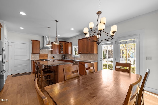 dining area featuring recessed lighting, ornamental molding, light wood finished floors, and a notable chandelier